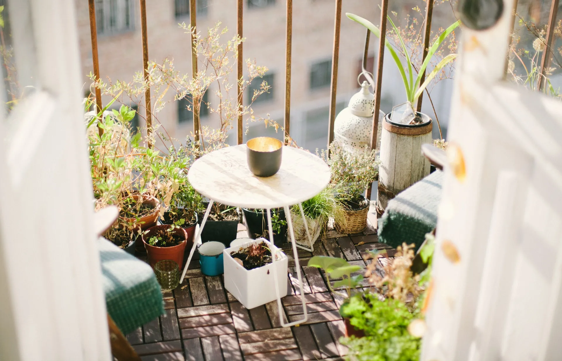 Un balcon urbain aménagé en potager permacole avec bacs profonds, aromatiques, légumes, fleurs mellifères et treillis vertical, vu à hauteur de jardinier.